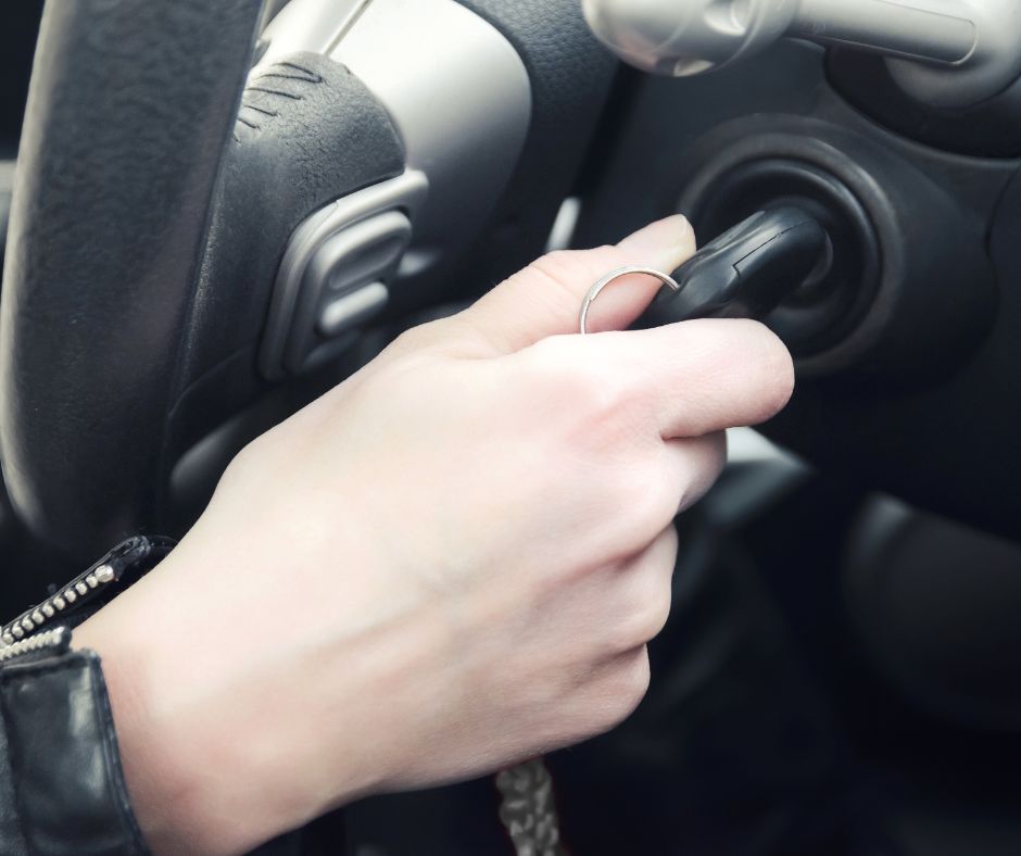 A locksmith carefully extracting a stuck key from a car's ignition.