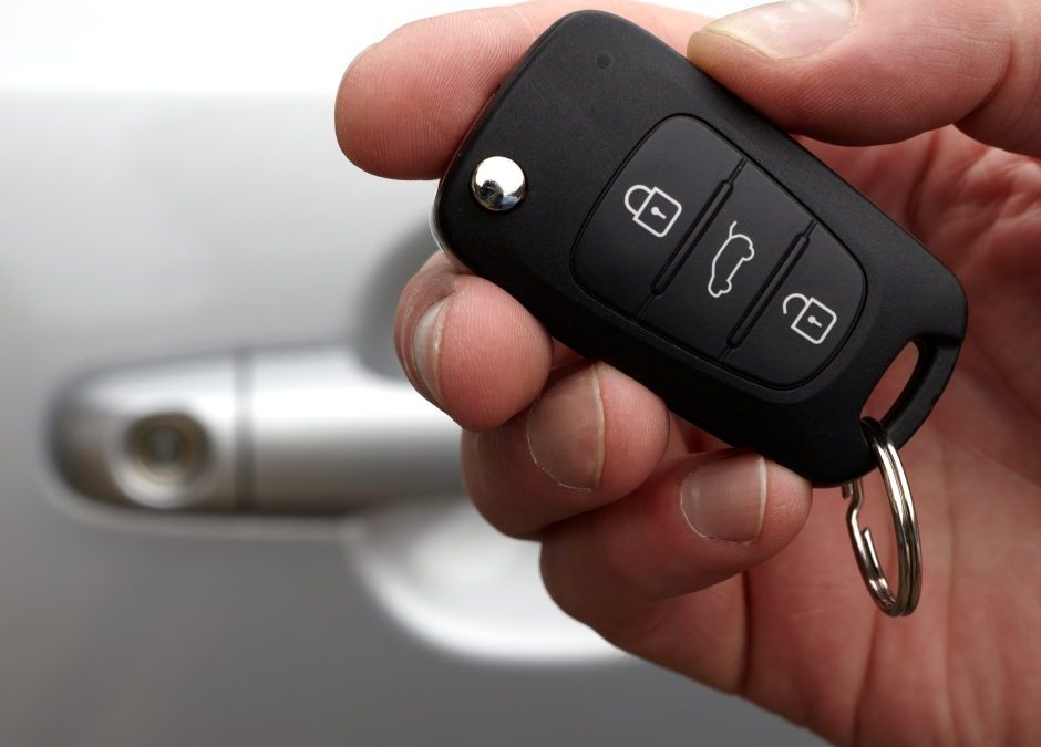 A sleek transponder key next to a modern car.
